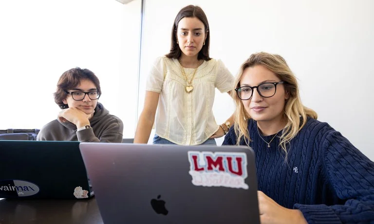 Three students looking at a laptop screen
